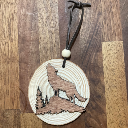 Wooden ornament with a wolf laser-cut design in a light stain on a natural wood round. Tied with a black leather cord and a round wooden bead for embellishment.